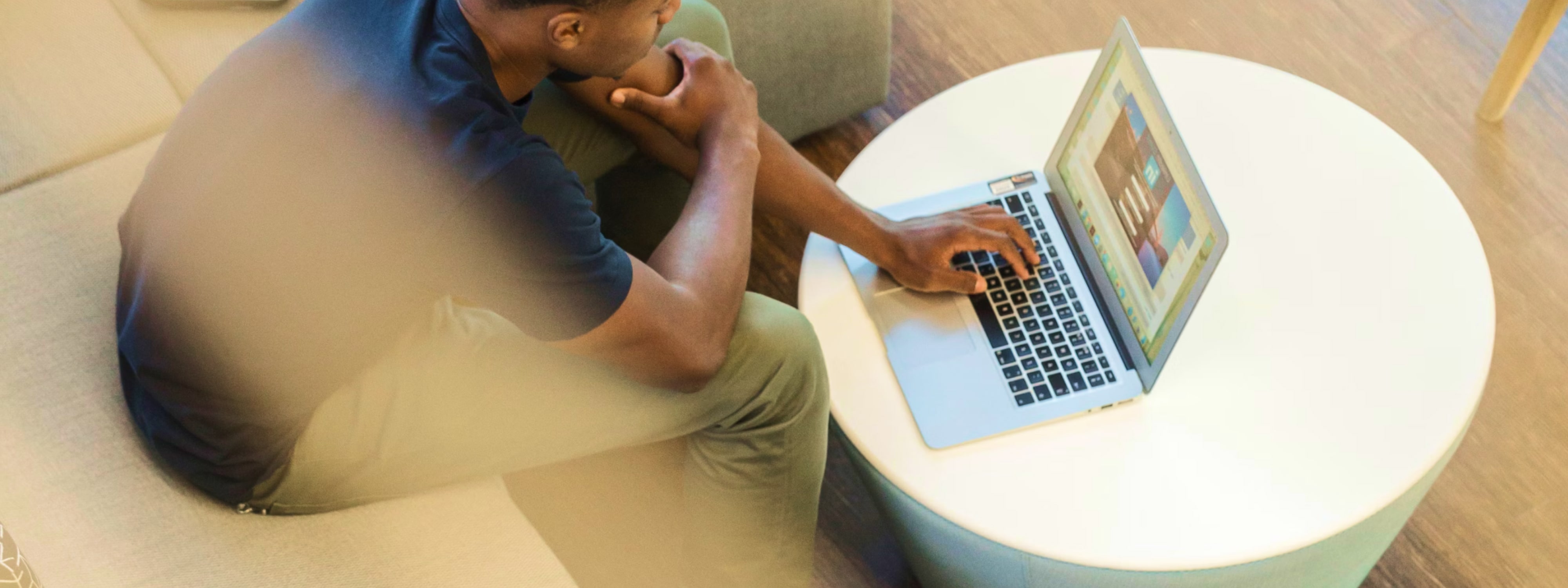 Person working on laptop at round table with thoughtful pose